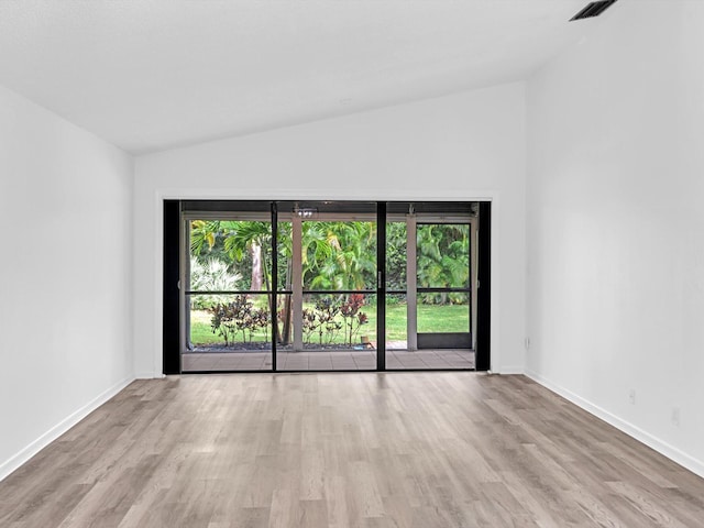 empty room featuring light hardwood / wood-style floors, a healthy amount of sunlight, and lofted ceiling