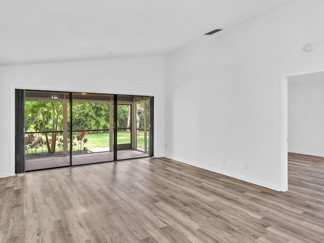 spare room featuring light wood-type flooring and high vaulted ceiling