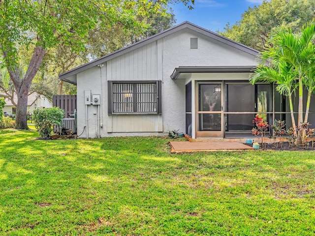 rear view of house with central air condition unit, a sunroom, and a yard