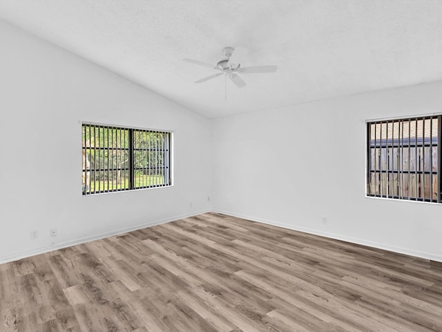 spare room featuring light wood-type flooring, lofted ceiling, a textured ceiling, and ceiling fan