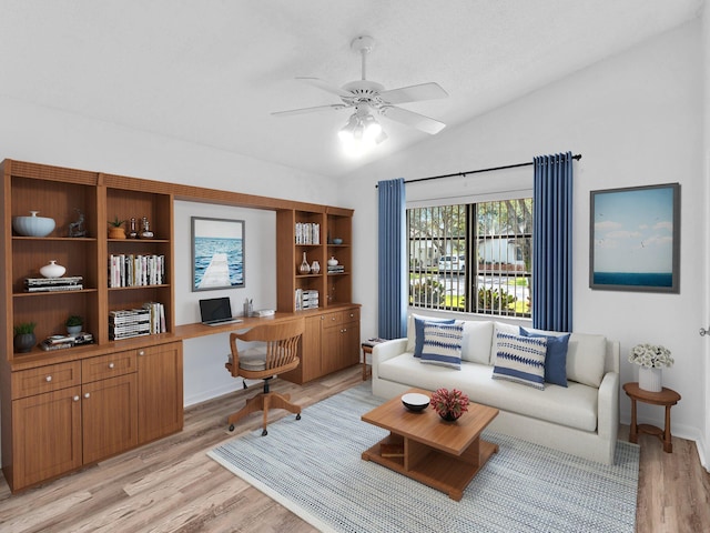 living room with built in desk, ceiling fan, lofted ceiling, and light hardwood / wood-style floors