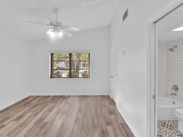 interior space featuring a textured ceiling, light hardwood / wood-style floors, ceiling fan, and vaulted ceiling