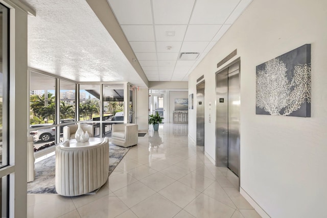 corridor featuring elevator, tile patterned flooring, and a drop ceiling