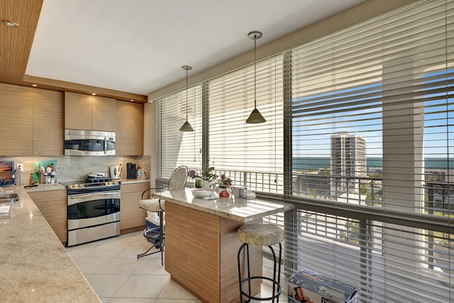 kitchen with stainless steel appliances, light stone countertops, a kitchen bar, backsplash, and pendant lighting