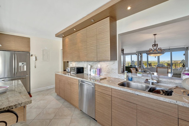 kitchen featuring appliances with stainless steel finishes, light tile patterned floors, decorative backsplash, sink, and a chandelier