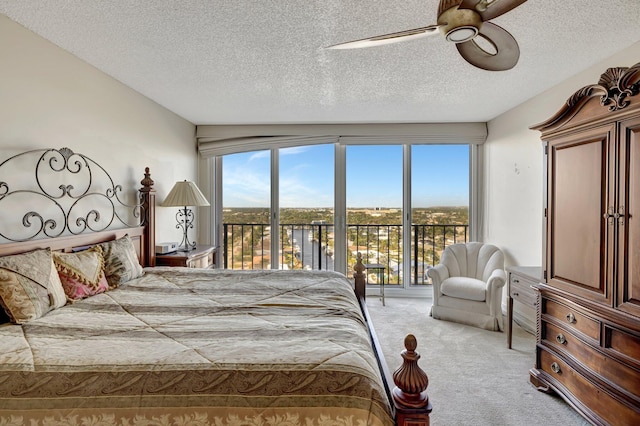 bedroom with a textured ceiling, access to outside, light colored carpet, and ceiling fan