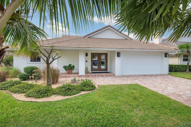 ranch-style home featuring french doors, a front yard, and a garage