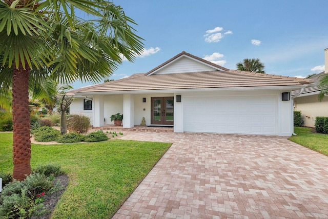 view of front of house with french doors, a front yard, and a garage