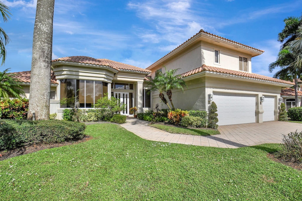 mediterranean / spanish house with a garage and a front lawn