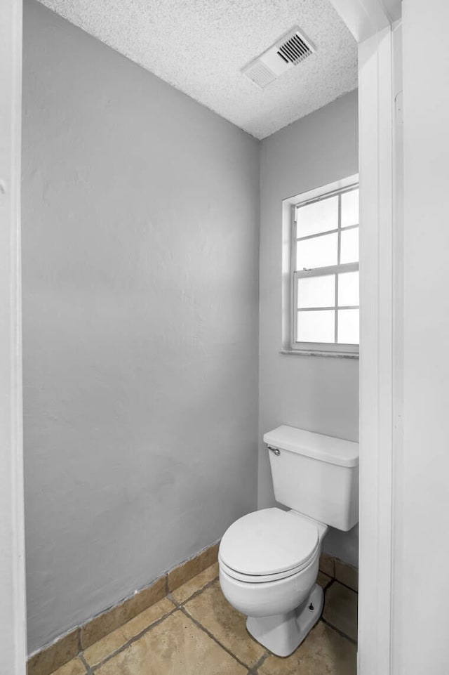 bathroom with toilet and a textured ceiling