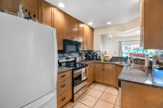 kitchen featuring sink, tasteful backsplash, white fridge, stainless steel range with electric stovetop, and light tile patterned floors