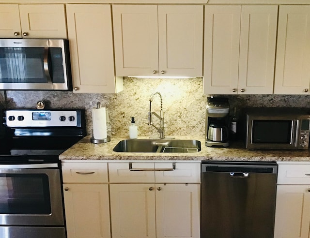 kitchen featuring tasteful backsplash, white cabinetry, sink, and appliances with stainless steel finishes