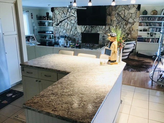 kitchen with a fireplace, light hardwood / wood-style flooring, a kitchen island, and dark stone countertops