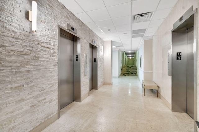 hallway with a drop ceiling and elevator