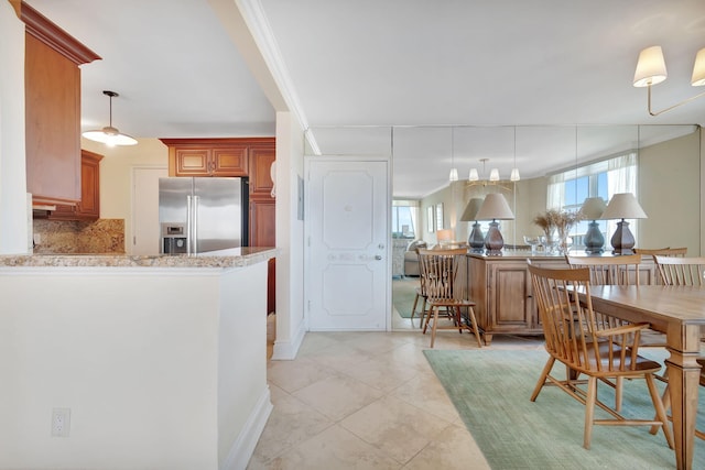 kitchen featuring backsplash, light tile patterned floors, pendant lighting, stainless steel refrigerator with ice dispenser, and kitchen peninsula