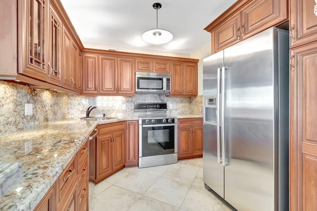 kitchen with light stone counters, decorative backsplash, hanging light fixtures, sink, and appliances with stainless steel finishes