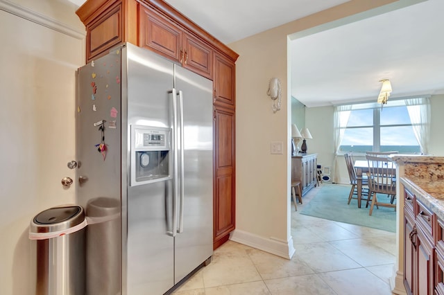 kitchen with light stone countertops, light tile patterned floors, and stainless steel fridge