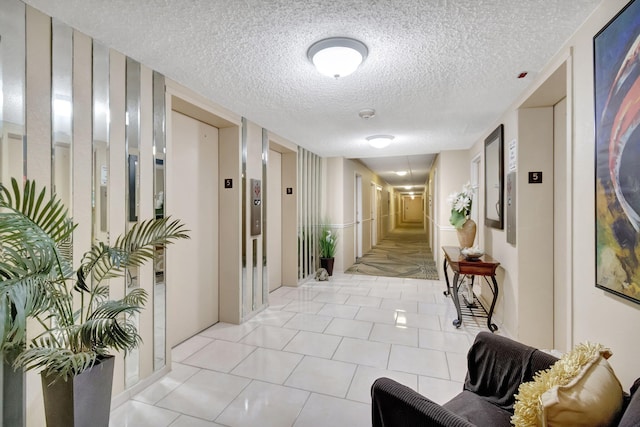 corridor with a textured ceiling and light tile patterned floors