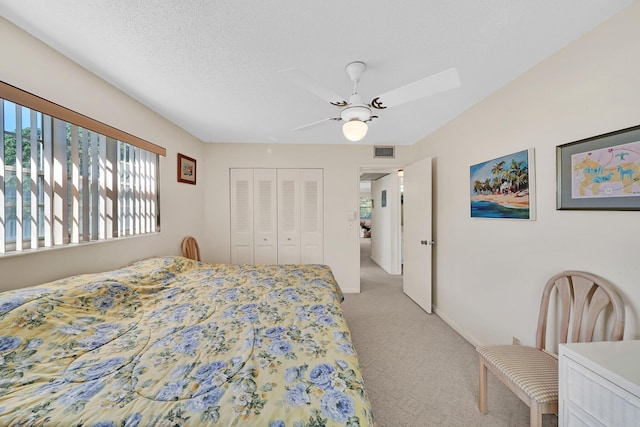 carpeted bedroom featuring ceiling fan, a closet, and a textured ceiling