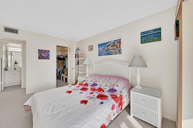 carpeted bedroom with ensuite bath, a walk in closet, and a closet