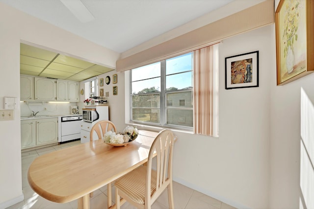 dining room with sink, light tile patterned flooring, and a drop ceiling