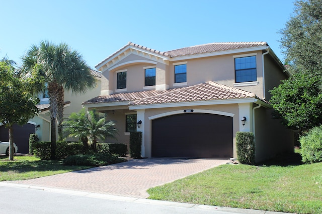 mediterranean / spanish home featuring a garage and a front lawn