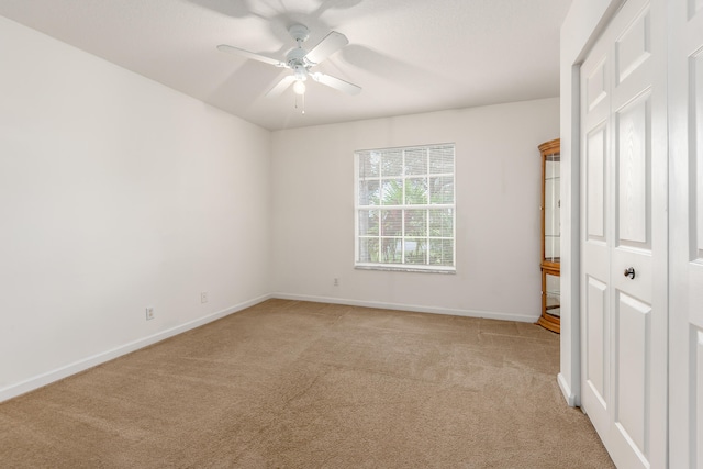 unfurnished bedroom featuring light colored carpet, ceiling fan, and a closet