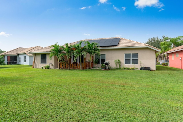 308 SW Egret Lndg, Port Saint Lucie, FL 34953 - back of property featuring solar panels, stucco siding, a lawn, and a tile roof