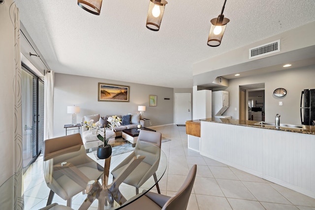 dining area with sink, light tile patterned flooring, and a textured ceiling