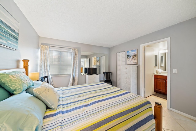 tiled bedroom with ensuite bathroom, a textured ceiling, and a closet