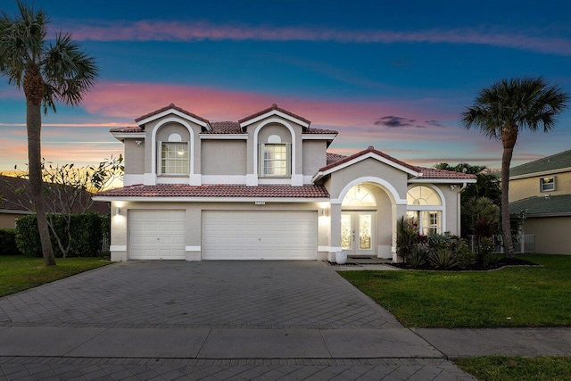 mediterranean / spanish-style home with a yard and a garage