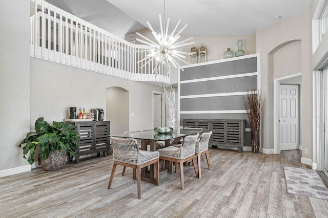 dining space with high vaulted ceiling, a notable chandelier, and hardwood / wood-style flooring