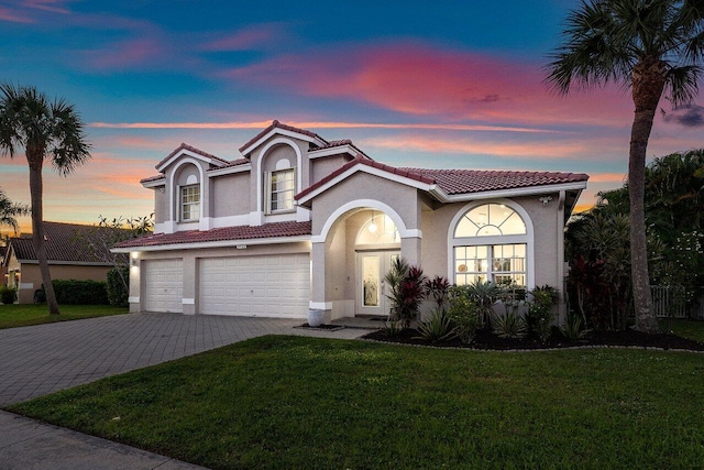 mediterranean / spanish house featuring a garage and a yard