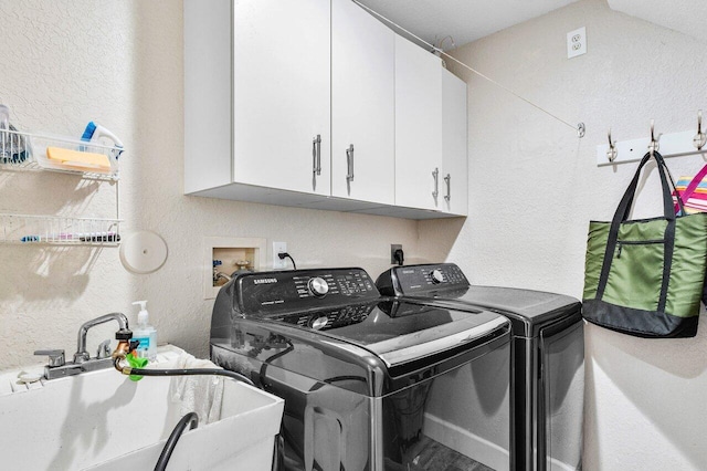 washroom with cabinets, independent washer and dryer, a textured ceiling, and sink