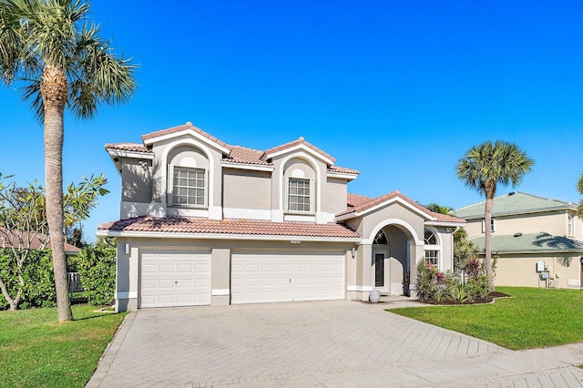 mediterranean / spanish-style home featuring a front lawn and a garage