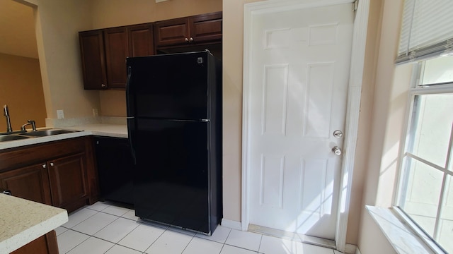 kitchen featuring dark brown cabinetry, black fridge, and sink