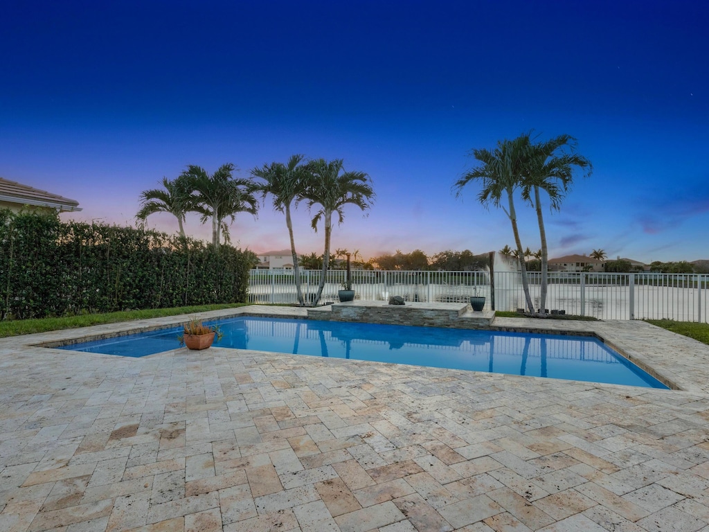 pool at dusk with a patio area