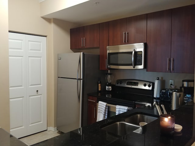 kitchen with dark stone countertops, appliances with stainless steel finishes, and sink