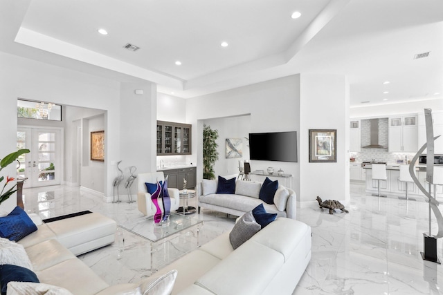 living room with a tray ceiling, french doors, and a high ceiling