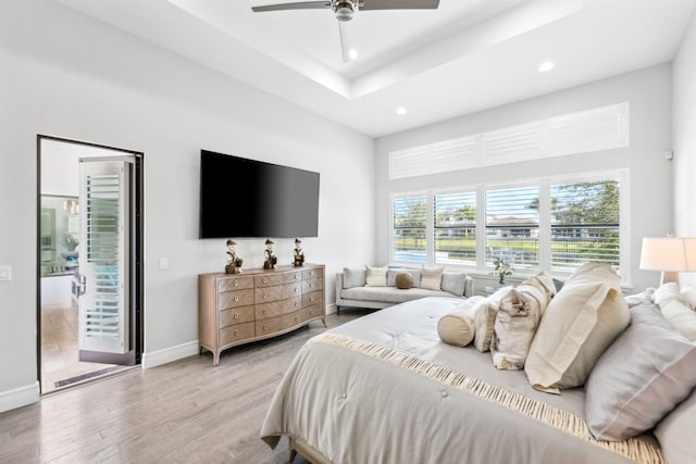 bedroom featuring ceiling fan, a tray ceiling, light hardwood / wood-style floors, and access to outside