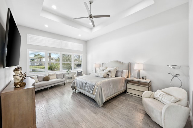 bedroom with hardwood / wood-style floors, a tray ceiling, and ceiling fan