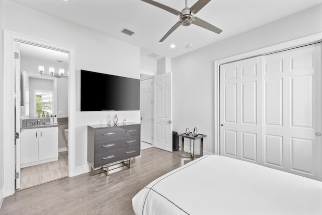 bedroom featuring ensuite bathroom, sink, light hardwood / wood-style flooring, ceiling fan, and a closet