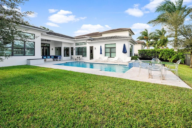 rear view of house featuring a fenced in pool, a patio area, ceiling fan, and a lawn