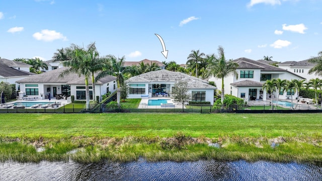 back of property with a water view, a yard, and a patio