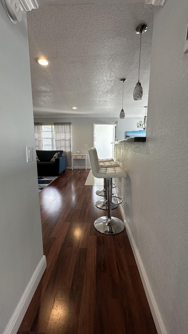 corridor with dark hardwood / wood-style floors and a textured ceiling