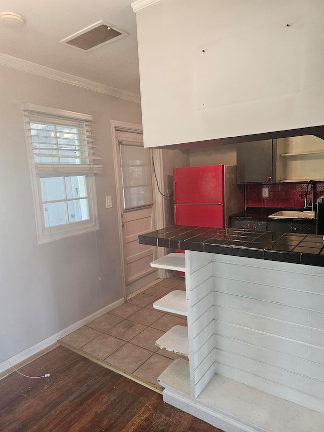 kitchen featuring sink, refrigerator, crown molding, tile counters, and dark hardwood / wood-style flooring