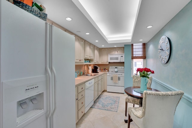 kitchen with a raised ceiling, sink, light tile patterned floors, and white appliances