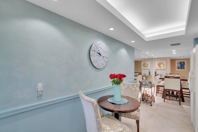 tiled dining area with a raised ceiling