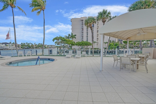 view of swimming pool featuring a patio area, ceiling fan, and a water view