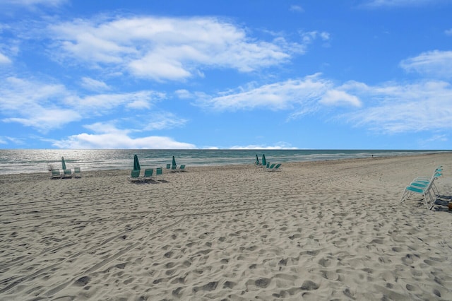 view of property's community with a water view and a beach view